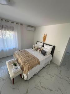 a white bedroom with a large bed and a table at Luka Vacation House in Ulcinj