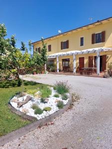 a large yellow building with a gravel driveway at appartamento Podere i Renai in Santa Maria a Monte