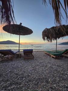 a beach with umbrellas and chaise lounges on the beach at Maxola's Dream Orikum in Orikum