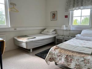 a bedroom with two beds and two windows at Sköna Rum Fryksta in Kil