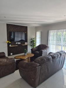 a living room with two leather couches and a tv at Nombelas Cottage in Westville