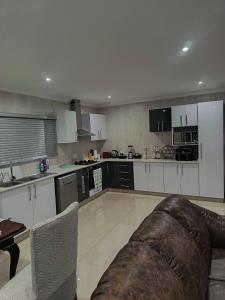 a kitchen with white cabinets and a couch in it at Nombelas Cottage in Westville