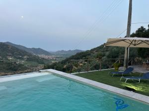 a swimming pool with an umbrella and a table and chairs at Villa Luca e Vale in Graniti