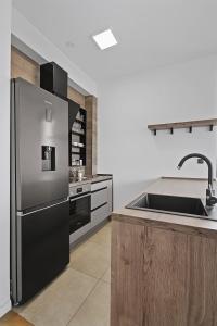 a kitchen with a stainless steel refrigerator and a sink at Azure Bay Apartments in Donja Lastva