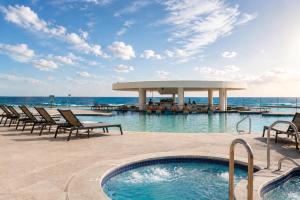 a swimming pool with chairs and a gazebo at Updated Beachfront Condo on Sandy Beach, Las Palmas Resort, 24hrs Security, Free Parking, Free Wi-Fi in Puerto Peñasco