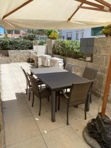 a wooden table and chairs under an umbrella at Casa dos Paralelos RC in Moledo