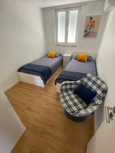 two beds and a chair in a small room at Casa dos Paralelos RC in Moledo