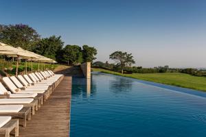 a pool with chairs and umbrellas on a wooden deck at Hotel Fasano Boa Vista in Pôrto Feliz