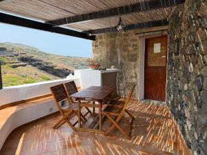 a table and chairs on a balcony with a stone wall at Dammuso Ziloto - Cala Levante & Arco dell'Elefante in Pantelleria