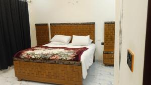 a bedroom with a large bed with a wooden headboard at HD Smart Hotel in Kot Mergulla