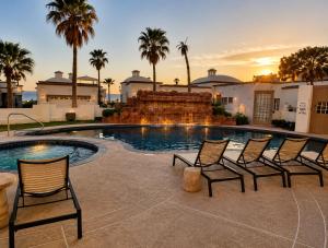 a group of chairs sitting around a swimming pool at Updated Beachfront Condo on Sandy Beach, Las Palmas Resort, 24hrs Security, Free Parking, Free Wi-Fi in Puerto Peñasco