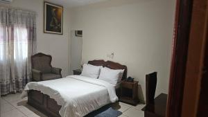 a bedroom with a bed and a chair and a television at Hôtel Cauris d'Or de Bouaké in Bouaké