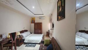 a room with two beds and a desk in it at Hôtel Cauris d'Or de Bouaké in Bouaké
