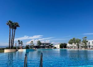 a large swimming pool with blue water and palm trees at BR Tale in Lezhë