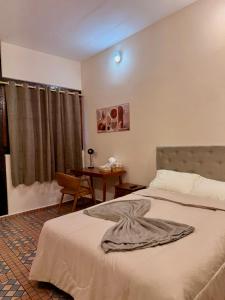 a bedroom with a bed and a table with a desk at Pousada Nhá Luz in Salesópolis