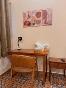 a wooden desk with a chair and pictures on the wall at Pousada Nhá Luz in Salesópolis