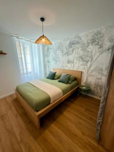 a bedroom with a bed with a wall with trees on it at Le Salon des Voyageurs - Appartement Climatisé avec Terrasse et Parking Gratuit à Proximité in Dole