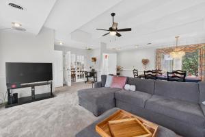a living room with a gray couch and a flat screen tv at Muirs Chapel Retreat in Greensboro