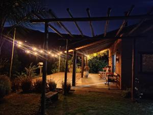 a pergola with lights in a yard at night at Alto Maanaim in Sapucaí-Mirim
