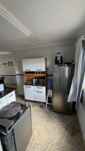 a kitchen with a stainless steel refrigerator and white cabinets at Cobertura de Frente Para o Mar e Piscina Village das Ondas in Piúma