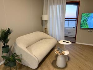 a living room with a chair and two tables at קו המים - Waterline סוויטות עם גקוזי הכי קרוב לים in Netanya