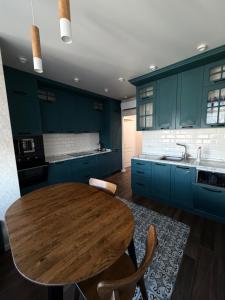 a kitchen with a wooden table and blue cabinets at 56 Жемчужина in Odesa