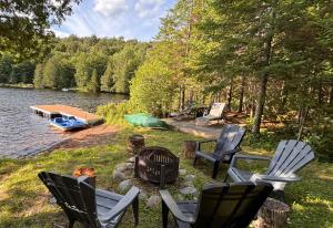 a group of chairs and a campfire next to a lake at L'Opie in Saint Adolphe D'Howard