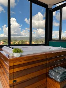 a jacuzzi tub in a room with large windows at Residencial Canto dos Passarinhos - Loft e Apartamentos in Alto Paraíso de Goiás