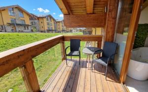a balcony with two chairs and a table on it at Jasna Chalet - Chopok view Apartment with sauna and whirlpool bathtub in Belá