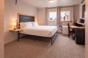 a bedroom with a large white bed and a desk at Highliner Suites Hotel in Anchorage