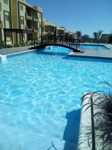 a large blue swimming pool with a bridge at Tavira شاليه in Ras Sedr +20 photos