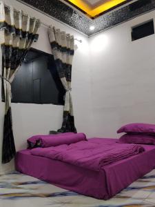 a bedroom with a bed with purple sheets and curtains at Homestay SeAngel in Labuan Bajo