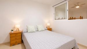 a white bedroom with a bed and a window at Apartment with pool in Cala Millor in Cala Millor +14 photos