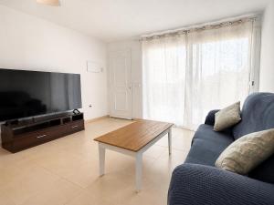 a living room with a couch and a tv and a table at Apartment with pool in Cala Millor in Cala Millor