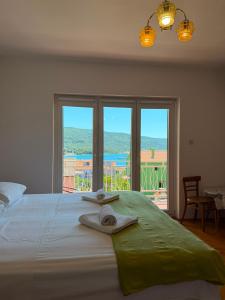 a bedroom with a bed with two towels and a window at Apartments Marija in Cres