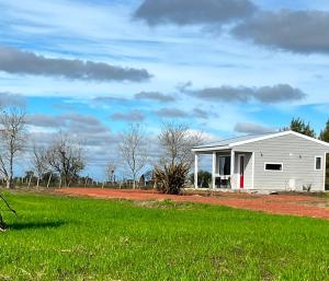 a white shed in a field next to a grass field at Carmela, Colonia Estrella in Carmelo