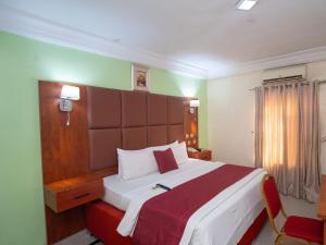 a bedroom with a large bed with a red blanket at Charriot Hotels in Abuja +30 photos
