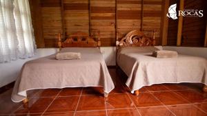 two beds in a room with wooden walls at Ciudad de Las Rocas in La Fortuna Gallo Giro