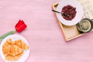 a table with a plate of pastries and a red rose at Hotel Volga EGG Grand Inn Near Delhi Airport in New Delhi +17 photos