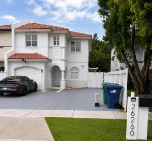 a white house with a car parked in a driveway at Rosa Bella Comfort Suite in Homestead