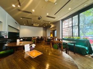 a dining room with tables and chairs and windows at パークホテル楽々園 in Maebashi