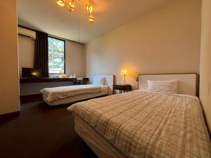 a hotel room with two beds and a window at パークホテル楽々園 in Maebashi +66 photos