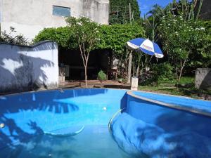 a blue swimming pool with an umbrella at Casa grande in Serra