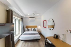 a bedroom with a bed and a desk and a mirror at Townhouse Habitat New Town Rooms & Party Spaces in Kolkata