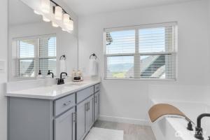 a white bathroom with a sink and a tub and two windows at Retro Ski Chalet in Heber City +47 photos