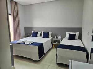a bedroom with two beds with blue and white pillows at Melges Apart Hotel in Pontes e Lacerda