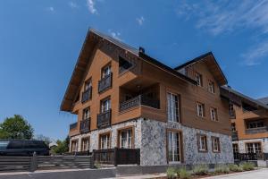 an apartment building with a car parked in front of it at Motherland Chalets in Žabljak