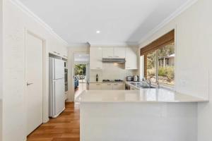 a kitchen with white appliances and a large window at Davali at Mogo in Mogo