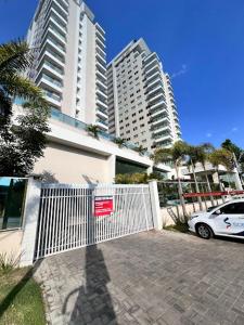 a car parked in front of a white gate with tall buildings at Studio Design 305 in Sobral