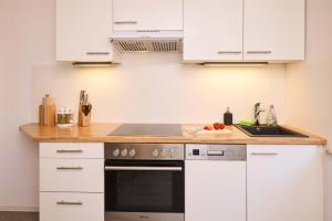 a kitchen with white cabinets and a stove top oven at FeWo Alte Mainbrücke in Würzburg +25 photos